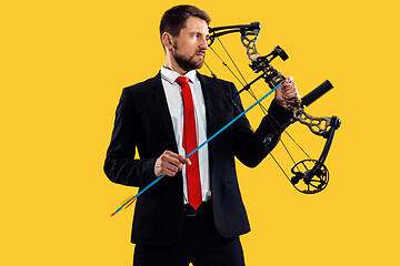 Image showing Businessman aiming at target with bow and arrow, isolated on yellow background