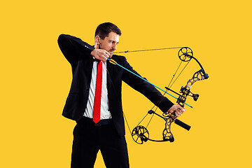 Image showing Businessman aiming at target with bow and arrow, isolated on yellow background