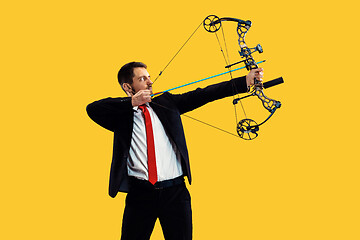 Image showing Businessman aiming at target with bow and arrow, isolated on yellow background