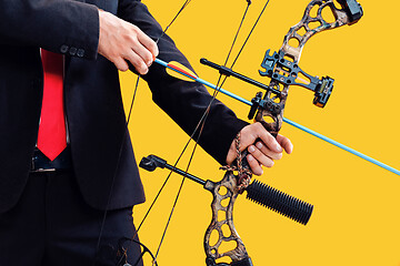 Image showing Businessman aiming at target with bow and arrow, isolated on yellow background