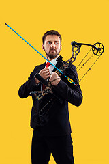 Image showing Businessman aiming at target with bow and arrow, isolated on yellow background