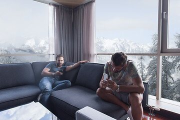 Image showing two young men using a mobile phones  at home