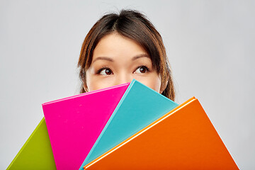 Image showing asian woman or student hiding behind notebooks