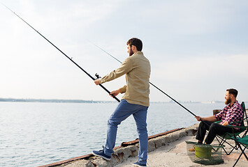Image showing male friends with fishing rods on sea pier