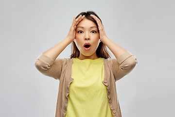 Image showing shocked asian woman holding to her head