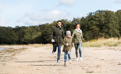 Image showing happy family running along autumn beach