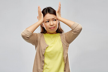 Image showing stressed asian woman holding to her head