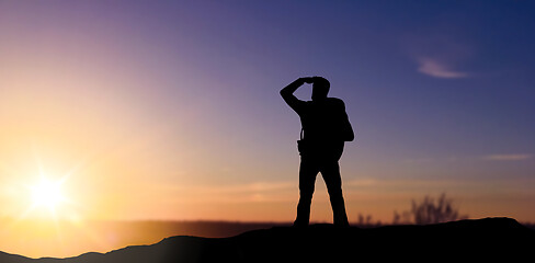 Image showing silhouette of tourist looking far away over sunset