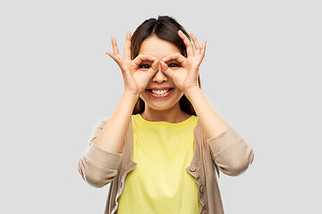 Image showing smiling asian woman looking through finger glasses