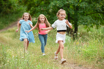 Image showing Kids, children running on green meadow, forest. Childhood and summertime