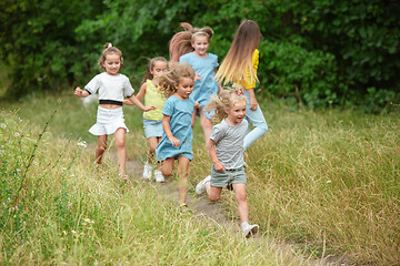 Image showing Kids, children running on green meadow, forest. Childhood and summertime