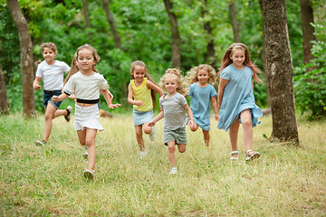 Image showing Kids, children running on green meadow, forest. Childhood and summertime