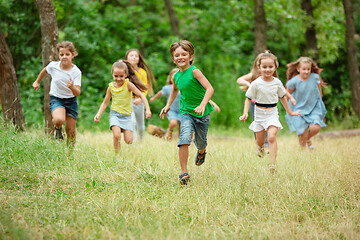 Image showing Kids, children running on green meadow, forest. Childhood and summertime