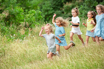 Image showing Kids, children running on green meadow, forest. Childhood and summertime