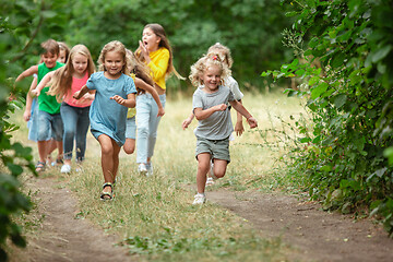 Image showing Kids, children running on green meadow, forest. Childhood and summertime