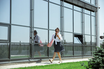 Image showing Young woman walking against glass\' wall in airport, traveler with small baggage, influencer\'s lifestyle