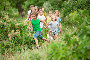 Image showing Kids, children running on green meadow, forest. Childhood and summertime