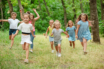 Image showing Kids, children running on green meadow, forest. Childhood and summertime