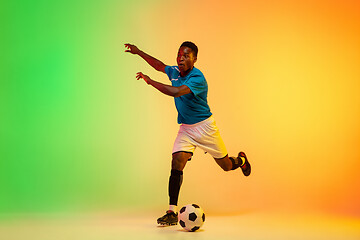 Image showing Male soccer, football player training in action isolated on gradient studio background in neon light