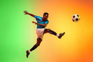 Image showing Male soccer, football player training in action isolated on gradient studio background in neon light