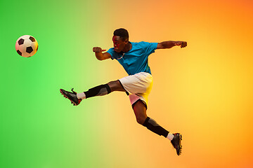 Image showing Male soccer, football player training in action isolated on gradient studio background in neon light