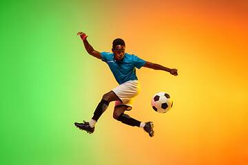 Image showing Male soccer, football player training in action isolated on gradient studio background in neon light