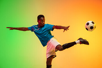 Image showing Male soccer, football player training in action isolated on gradient studio background in neon light