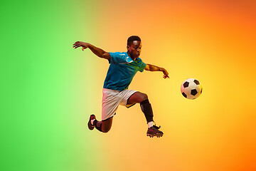 Image showing Male soccer, football player training in action isolated on gradient studio background in neon light