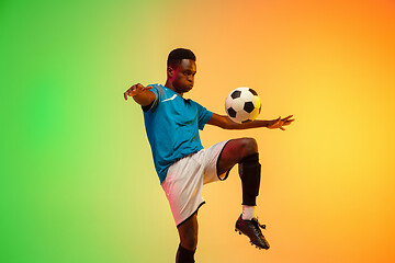 Image showing Male soccer, football player training in action isolated on gradient studio background in neon light