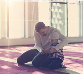 Image showing father and son in mosque praying and reading holly book quran to