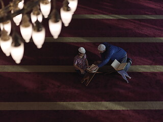 Image showing father and son in mosque praying and reading holly book quran to