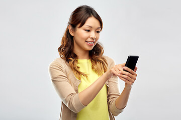 Image showing happy asian woman using smartphone