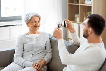 Image showing adult son photographing senior mother at home