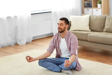 Image showing man meditating in lotus pose at home