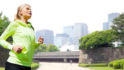 Image showing woman with earphones running at city park