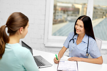 Image showing female doctor with clipboard and patient at clinic