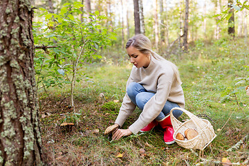 Image showing young woman picking mushrooms in autumn forest