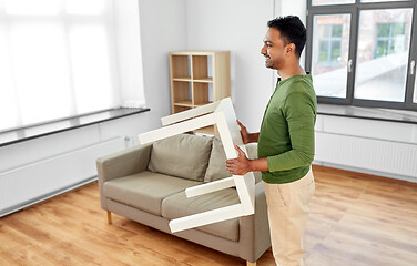 Image showing happy indian man holding coffee table at home