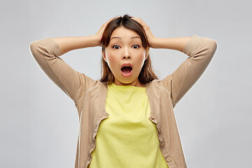 Image showing shocked asian woman holding to her head