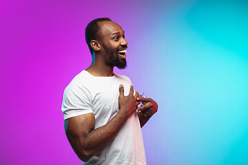 Image showing African-american young man\'s portrait on gradient studio background in neon