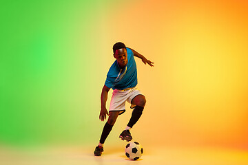 Image showing Male soccer, football player training in action isolated on gradient studio background in neon light
