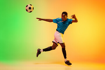 Image showing Male soccer, football player training in action isolated on gradient studio background in neon light