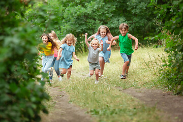 Image showing Kids, children running on green meadow, forest. Childhood and summertime