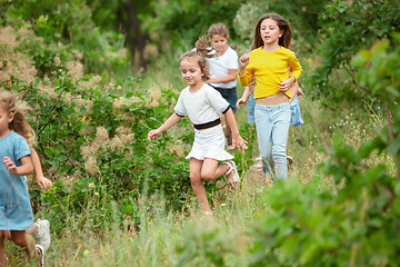 Image showing Kids, children running on green meadow, forest. Childhood and summertime