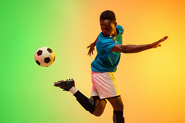 Image showing Male soccer, football player training in action isolated on gradient studio background in neon light