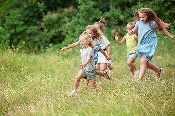 Image showing Kids, children running on green meadow, forest. Childhood and summertime