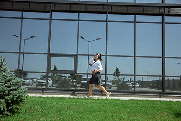 Image showing Young woman walking against glass\' wall in airport, traveler with small baggage, influencer\'s lifestyle