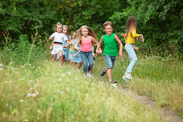 Image showing Kids, children running on green meadow, forest. Childhood and summertime