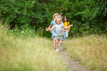 Image showing Kids, children running on green meadow, forest. Childhood and summertime