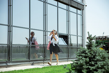 Image showing Young woman walking against glass\' wall in airport, traveler with small baggage, influencer\'s lifestyle
